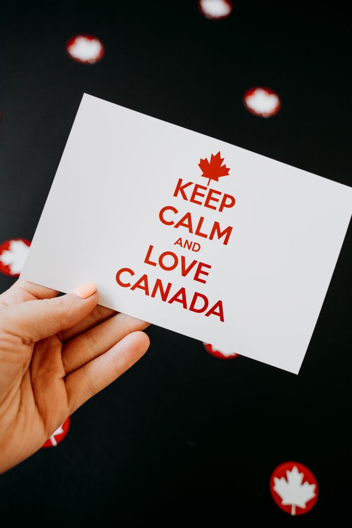 Hand holding a card with 'Keep Calm and Love Canada' text, perfect for Canada Day celebrations.